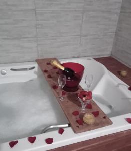 una bottiglia di vino e due bicchieri su una vasca da bagno di Pousada Jardim Coberto a Canela