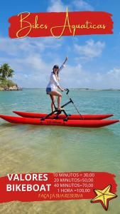 a woman on a red paddle board in the water at Pousada o Forte in Mangue Sêco