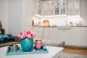 a table with a blue vase with pink flowers on it at Apartament Marta Luxury in Krynica Morska +31 photos