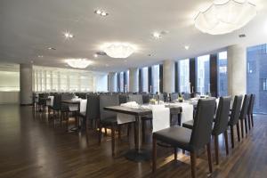 a dining room with tables and chairs and windows at Empire Riverside Hotel in Hamburg