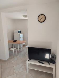 a living room with a tv and a clock on the wall at Strandhaus Adria in Ulcinj