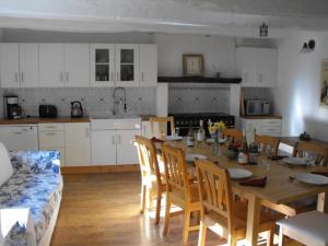 a kitchen with a table and chairs and a kitchen with white cabinets at Teag Beag in La Grée-Saint-Laurent