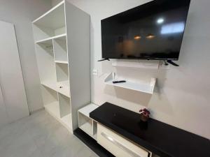 Central Praias Suite 1 في كابو فريو: غرفة معيشة مع تلفزيون على الحائط