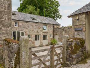an old stone cottage with a wooden gate and a house at Butterbrook Coach House in Harford