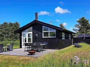 a black cabin with a table and chairs on a deck at 6 person holiday home in Hirtshals in Hirtshals