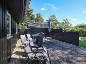 a group of chairs on a deck with an umbrella at 6 person holiday home in Hirtshals in Hirtshals