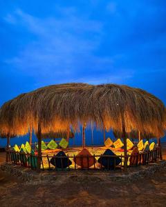 a straw hut with chairs under it on the beach at sea horse in Nuweiba