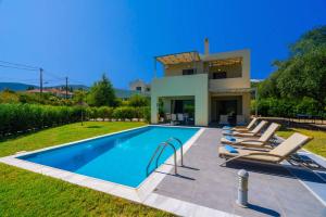 a villa with a swimming pool in front of a house at Villa Rubi by Villa Plus in Karavomylos