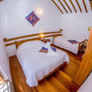 two beds in a room with wooden floors at Hostal El Grial in Cusco