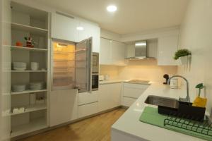 una cocina con armarios blancos y fregadero en Apartamento Confot / SBHome, en Noia