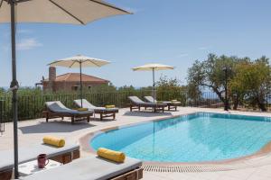 a swimming pool with lounge chairs and umbrellas at Villa Sandy Cove by Villa Plus in Spartia