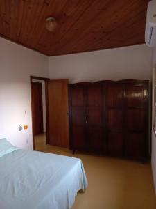 a bedroom with a white bed and wooden cabinets at Recanto Manga da Rosa - casinha de fazenda no centro da cidade in Olímpia +20 photos