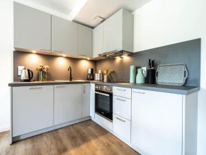 eine weiße Küche mit weißen Schränken und Geräten in der Unterkunft Dünenresidenz Prora - Ferienwohnung mit 2 Schlafzimmern und Balkon B3-2-3 in Binz + 2 Fotos