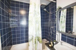 bagno piastrellato blu con vasca e doccia di Garden Tower flat a Londra Altre 10 foto