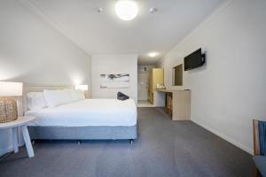 um quarto de hotel com uma cama e uma televisão em Woolgoolga Coast Motel em Woolgoolga