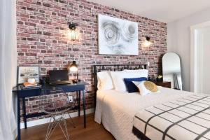 a bedroom with a brick wall and a bed and a desk at Jardin Suites Highfield in Moncton