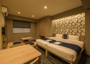 una camera d'albergo con 2 letti, una scrivania e un tavolo di KOKO HOTEL Residence Asakusa Kappabashi a Tokyo