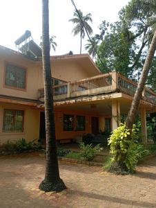 een huis met een balkon en 2 palmbomen bij Lobos villa in Calangute