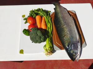 Un plato blanco con verduras y un pescado. en Amantani Pachatata Lodge en Ocosuyo