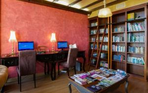 a library with a desk and two computers and bookshelves at Hotel Rural y SPA Kinedomus Bienestar in Aranda de Duero