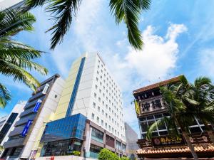 a tall white building in a city with palm trees at Hotel Abest Naha Kokusai Street in Naha
