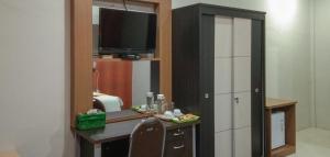 a room with a desk with a tv and a mirror at Edhotel Kusuma Atambua Mitra RedDoorz in Tatakiren