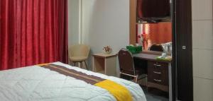 a bedroom with a bed and a desk and a television at Edhotel Kusuma Atambua Mitra RedDoorz in Tatakiren