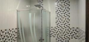 a glass shower in a bathroom with black and white tiles at Edhotel Kusuma Atambua Mitra RedDoorz in Tatakiren