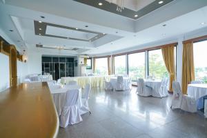 um salão de banquetes com mesas brancas e cadeiras brancas em Urbanview Hotel Pangkalpinang by RedDoorz em Kebinti