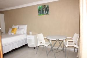 a bedroom with a bed and a table and chairs at Unit G Guest House in Ga-Mothiba