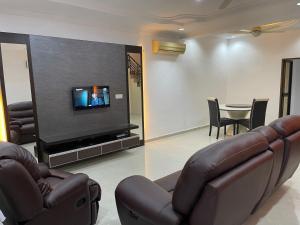 a living room with a couch and a tv and a table at Villa Prisha in Bayan Lepas