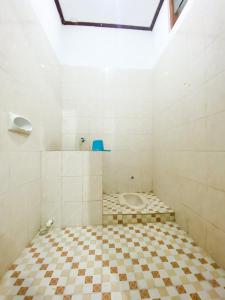 a bathroom with a toilet with a tiled floor at Homey Guesthouse Kertajaya (Syariah) in Surabaya