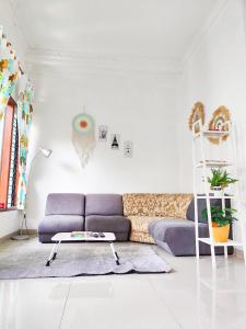 uma sala de estar com um sofá roxo e uma escada em Homey Guesthouse Kertajaya (Syariah) em Surabaya