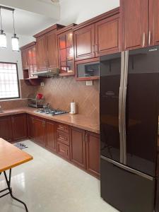 a kitchen with wooden cabinets and a black refrigerator at Villa Prisha in Bayan Lepas