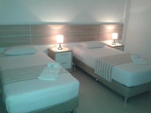 2 camas en una habitación de hotel con 2 lámparas en Hotel Salzburgo, en Ciudad del Este