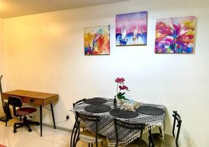 a room with a table with chairs and paintings on the wall at H family Cozy place at Verdi Cyberjaya in Cyberjaya