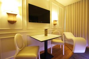 Habitación de hotel con mesa, sillas y TV. en Silk Motel en Pedroso