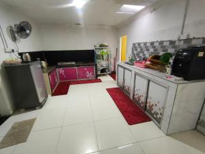 a kitchen with white floors and a red rug at Homestay Patonah 1 in Gerisik