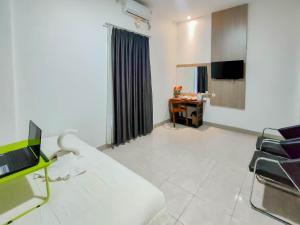a room with a couch and a tv and a desk at Urbanview Hotel Bagoes Sintang by RedDoorz in Sintang