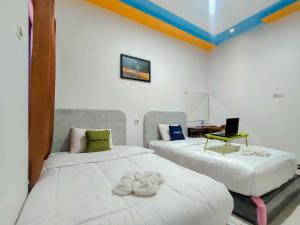 two beds in a room with a laptop on a desk at Urbanview Hotel Bagoes Sintang by RedDoorz in Sintang