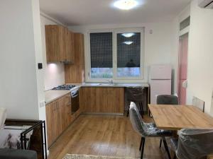 a kitchen with wooden cabinets and a table and a table and chairs at Apartament nemaipomenit, nou, in Complex Rezid Ared in Arad