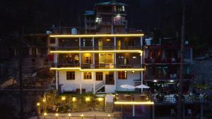 un gran edificio con luces delante de él por la noche en Wabi Sabi Riverside Hostel, en Kasol