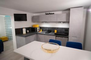 a kitchen with a white table and blue chairs at Rochecorbon Le Gite des Clouet "Labellisé Loire A Vélo" in Rochecorbon