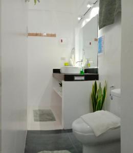 a white bathroom with a sink and a toilet at Corong Beach Resort in El Nido