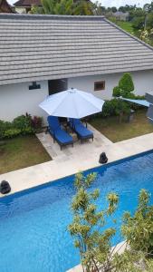 an umbrella and chairs next to a swimming pool at Kartika Villas in Lovina