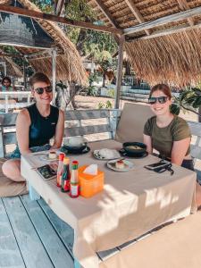 Dos mujeres sentadas en una mesa con comida. en Gita Gili Bungalow, en Gili Air