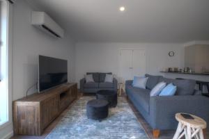 een woonkamer met een bank en een flatscreen-tv bij Albatross Retreat in Inverloch