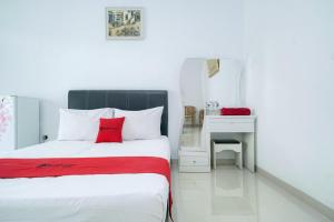 a bedroom with a bed and a desk with a red pillow at RedDoorz Syariah near RS Awal Bros Batam in Nagoya