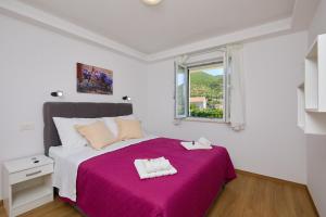- une chambre avec un grand lit et une couverture violette dans l'établissement Villa Larum, à Mokošica