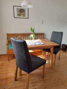 een houten eettafel met 2 stoelen en een vaas erop bij Ferienwohnung Ritzinger in Perlesreut